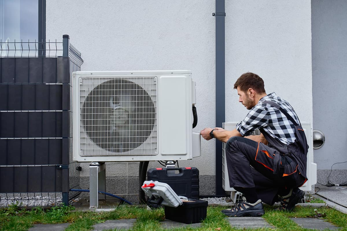 Professional HVAC technician checking refrigerant pressure on an outdoor residential air conditioning unit during routine maintenance.